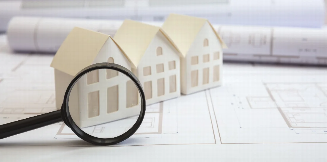 House models and a magnifying glass on architectural plans